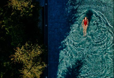 Frau schwimmt im Infinity Pool des Naturhotel Forsthofgut